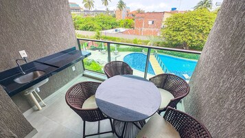 A balcony with a pool, outdoor furniture, and a view of buildings.