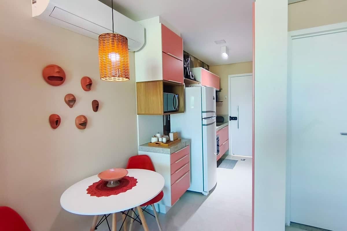 Une cuisine compacte équipée d’un réfrigérateur, d’un four à micro-ondes et d’une petite table à manger avec des chaises.