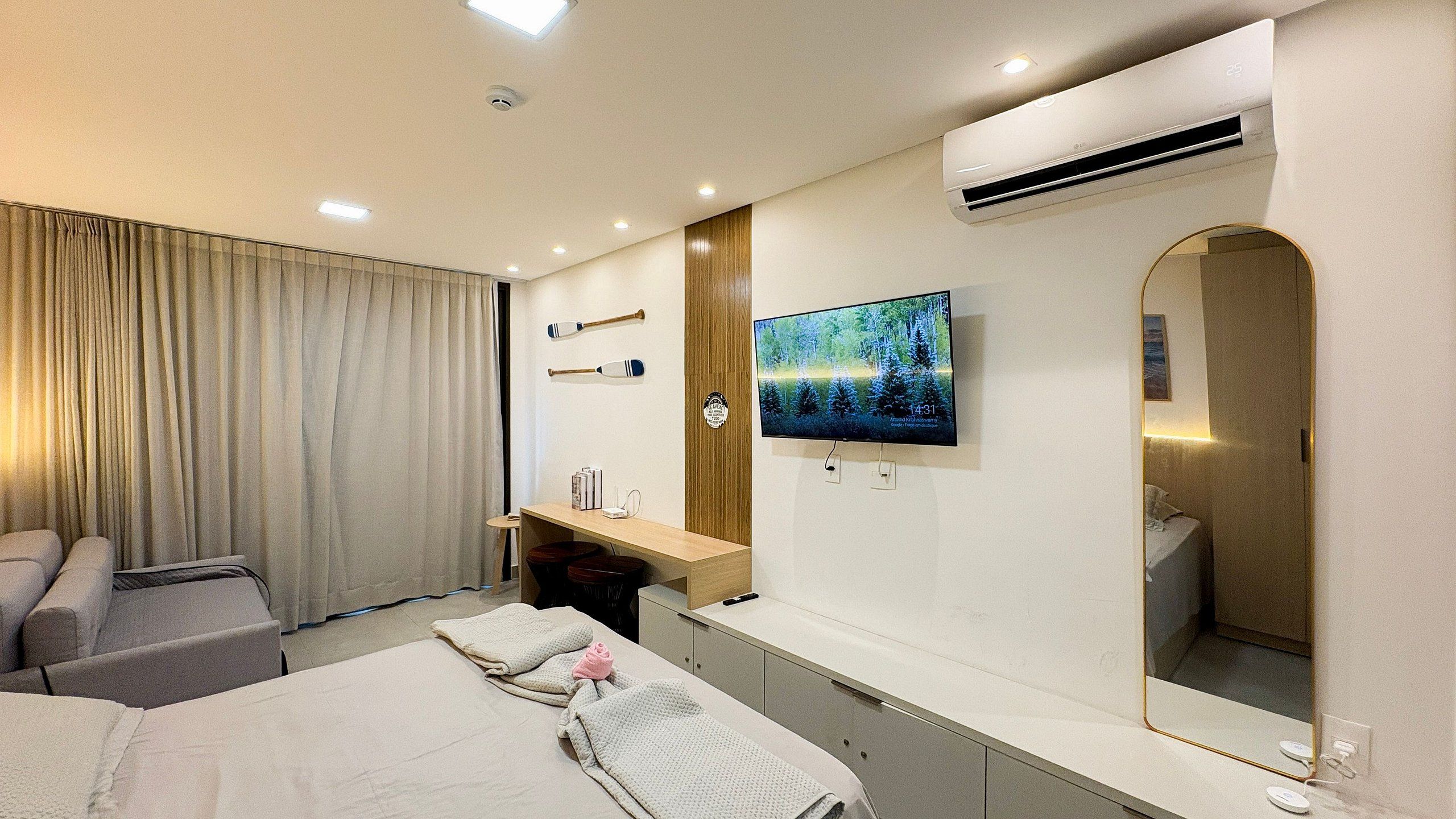 A hotel room with a bed, a TV, a desk, and a mirror.