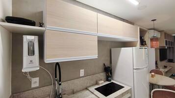 A compact kitchen with a built-in dishwasher, a small countertop, and a refrigerator.