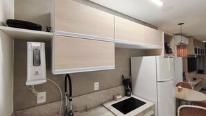 Uma cozinha compacta com máquina de lavar louça embutida, bancada pequena e frigorífico.