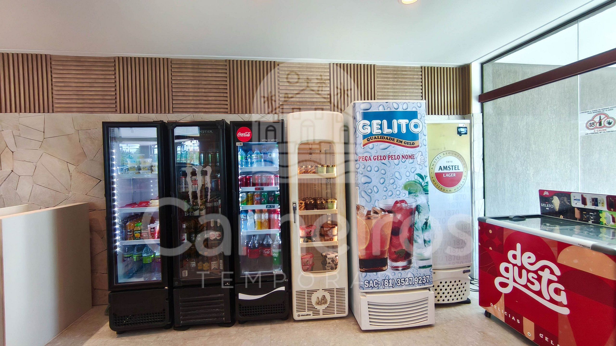 A row of beverage vending machines with various drink options, a large ice cream dispenser, and a red ice cream bar.