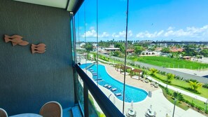 Un balcón con vista a una piscina y jardines.