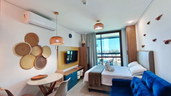 Habitación de hotel con cama, televisión, mesa de comedor y vistas a la ciudad.
