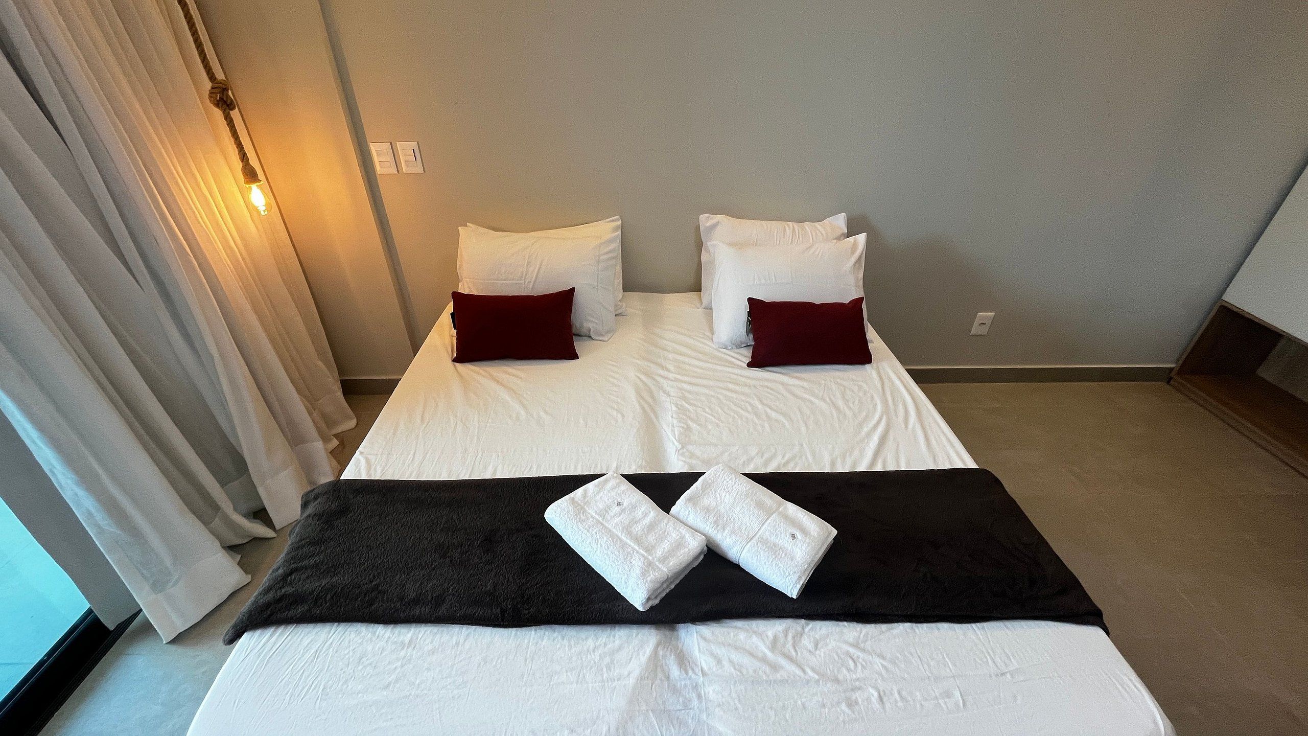 Una habitación de hotel con cama, almohadas, una manta y una toalla.