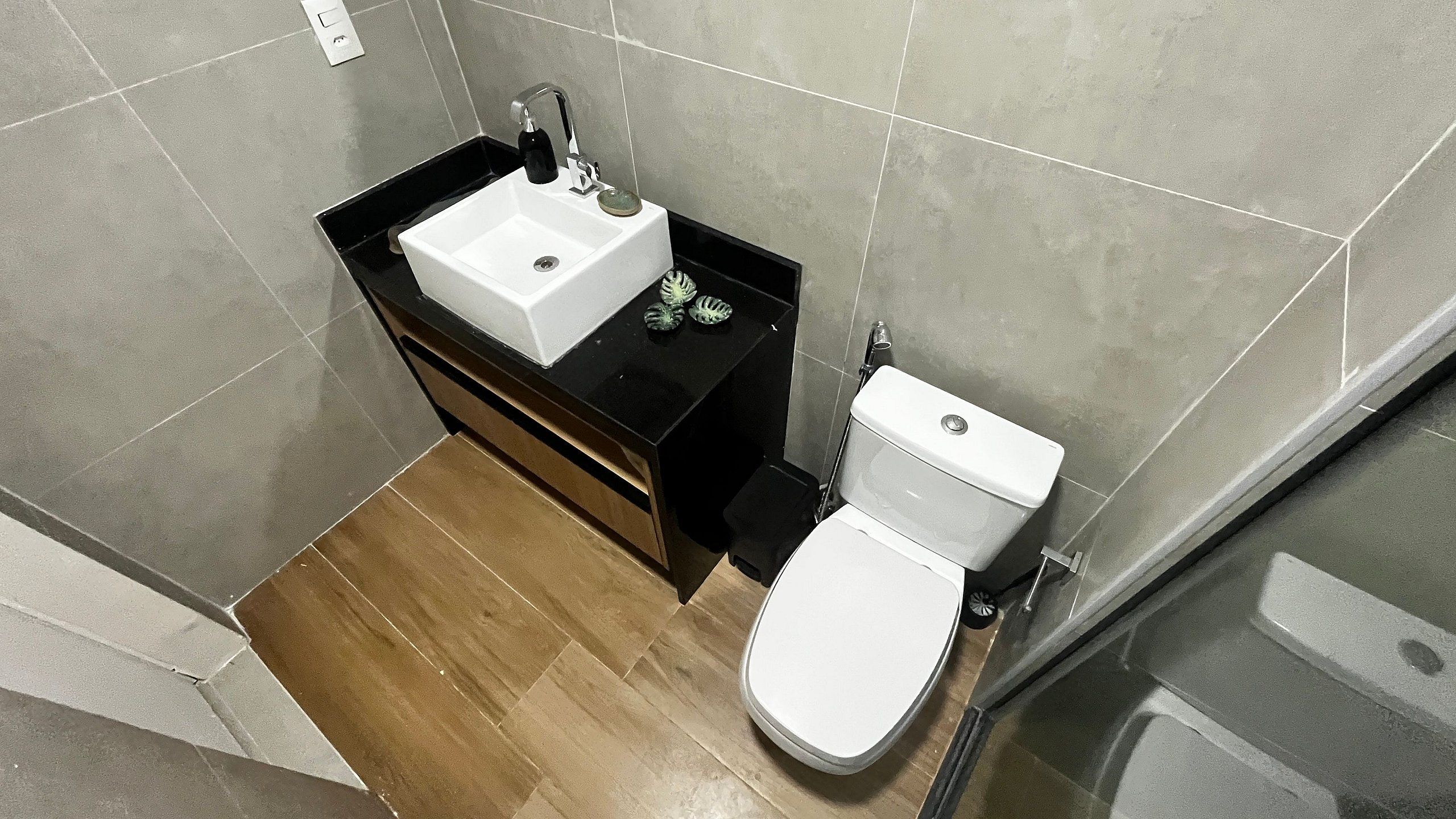 Ein Badezimmer mit einem weißen Waschbecken, einer schwarzen Arbeitsplatte und einer weißen Toilette.