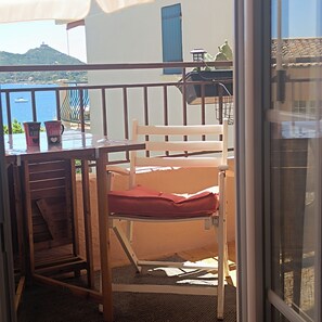 A balcony with a table, chairs, and a view of the sea.