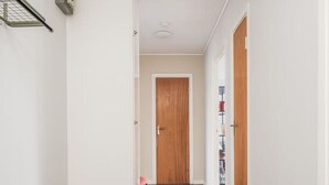 Un couloir avec un plancher en bois, des murs blancs et une porte en bois au fond.