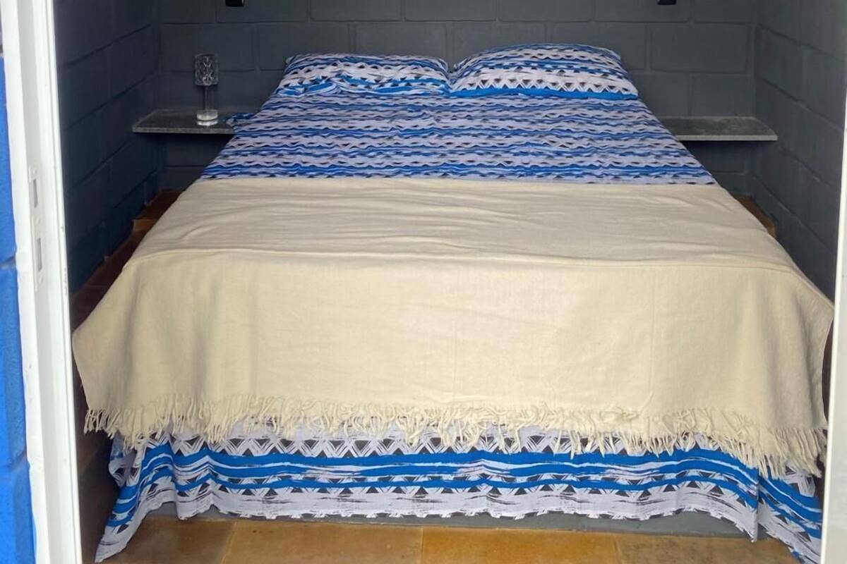 Un dormitorio ático pequeño y triangular con cama, mesita de noche y aire acondicionado de pared.
