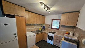 Una cocina compacta con gabinetes de madera, un refrigerador blanco, una estufa y un lavamanos.