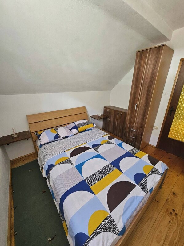 A bedroom with a wooden bed, a small bedside table, and a wardrobe.