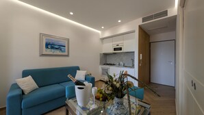A modern living room with a blue sofa, a glass coffee table with a vase of flowers, and a framed painting on the wall. - Mondello D'Amare (Palermo)