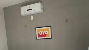 A room with two beds, an air conditioning unit, and a framed sign on the wall.