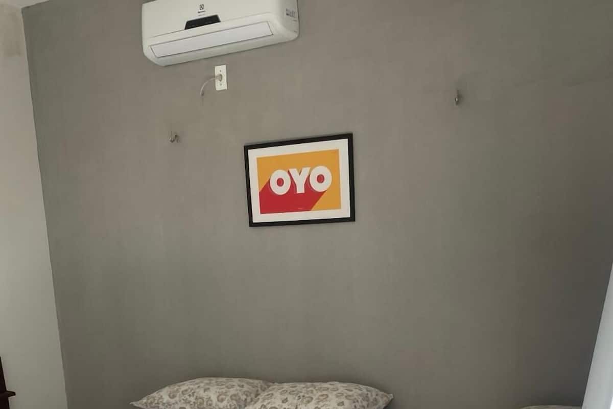 Une chambre avec deux lits, un appareil de climatisation et un panneau encadré accroché au mur.
