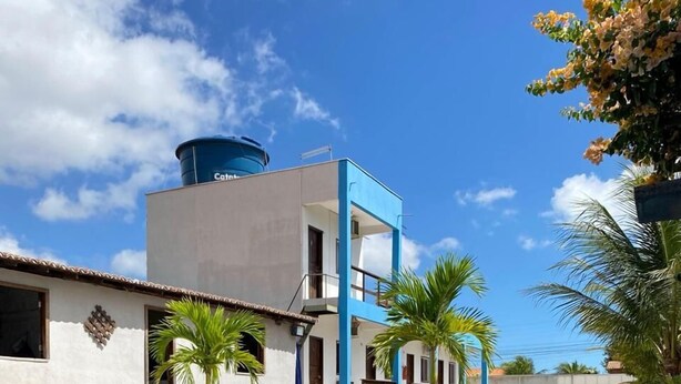 A modern hotel with a pool reflecting palm trees and a clear sky.