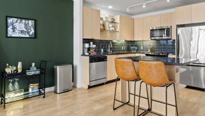 Una cocina moderna con armarios de madera, electrodomésticos de acero inoxidable y una barra con taburetes.