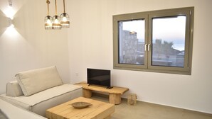 Uma sala de estar moderna com um sofá, mesa de centro de madeira e uma TV sobre um móvel de madeira.