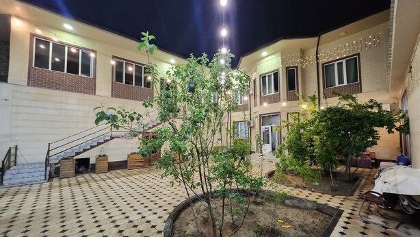 Un patio con suelo de baldosas, una escalera y un pequeño árbol.