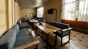 Un restaurante con una barra larga, mesas de madera y asientos tapizados en gris.