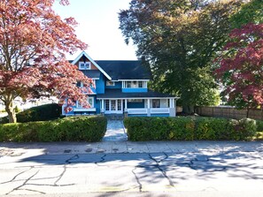 Una casa a due piani con facciata blu, un portico e una strada privata che conduce all'ingresso.