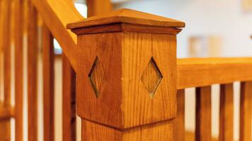Een houten trap met een leuning en een houten paal met diamantvormige uitsparingen.