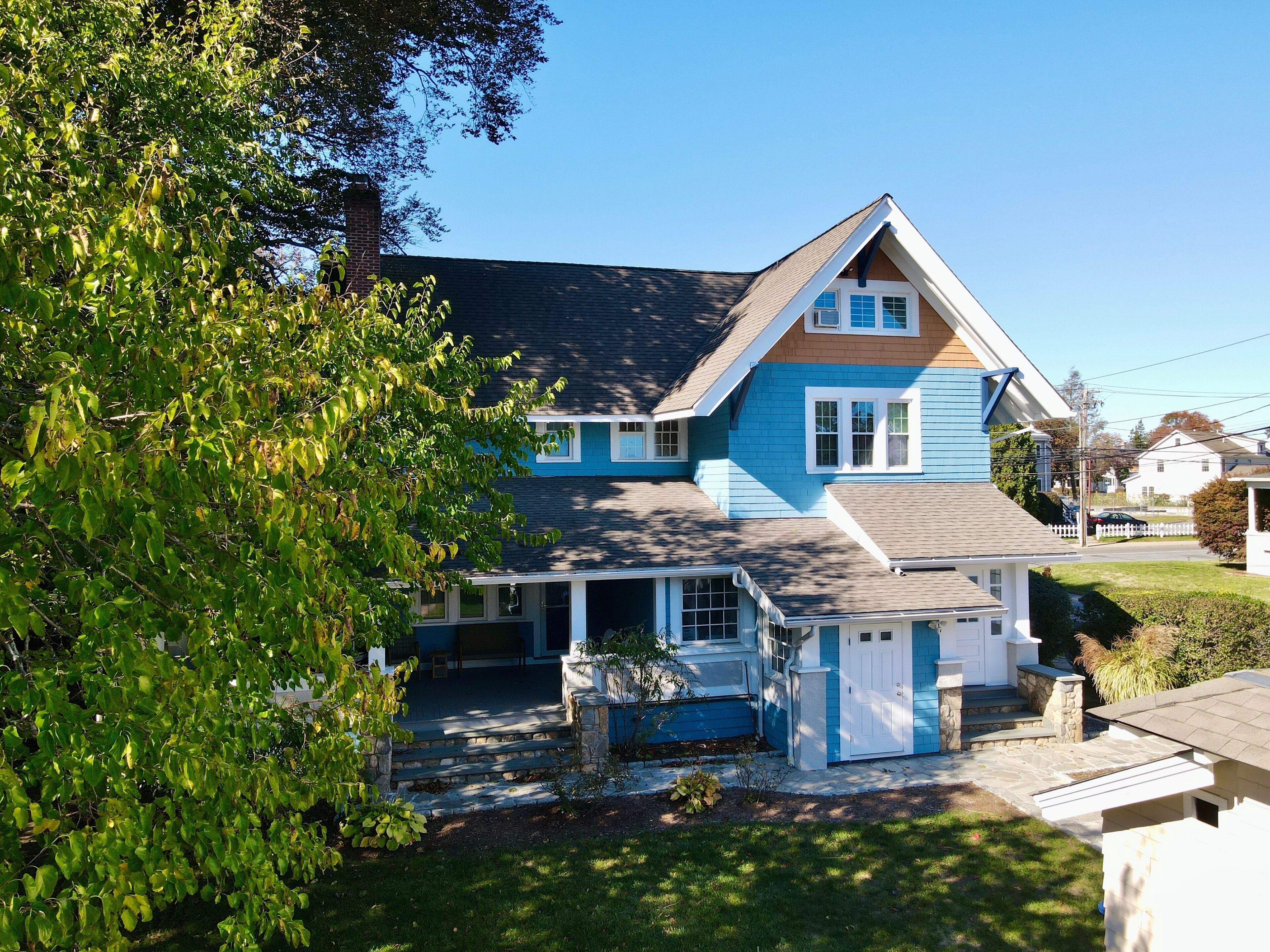 A two-story house with a front porch, a chimney, and a well-maintained lawn.