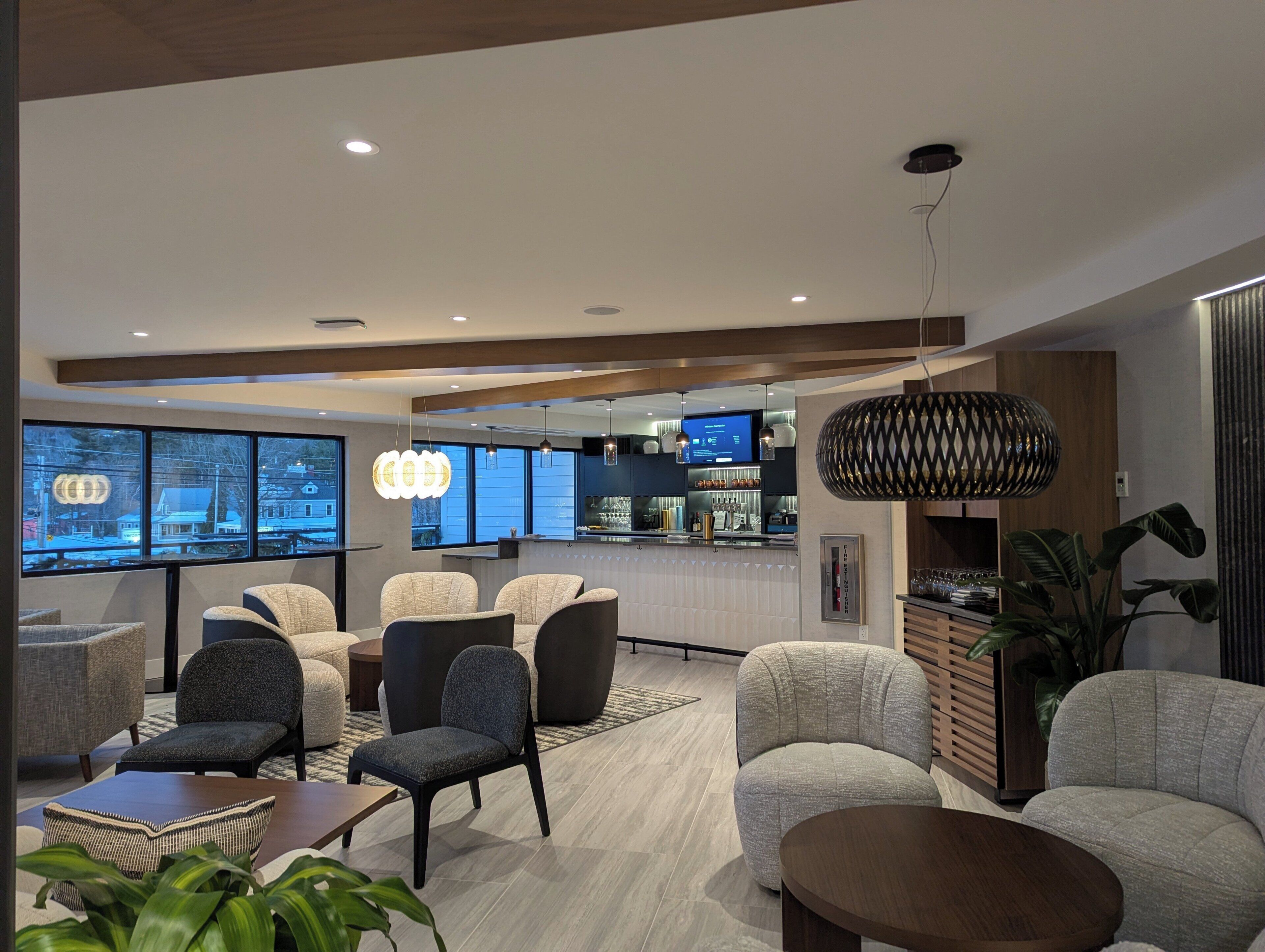 Un moderno vestíbulo de hotel con zonas de estar, un bar y amplios ventanales con vistas a la ciudad.