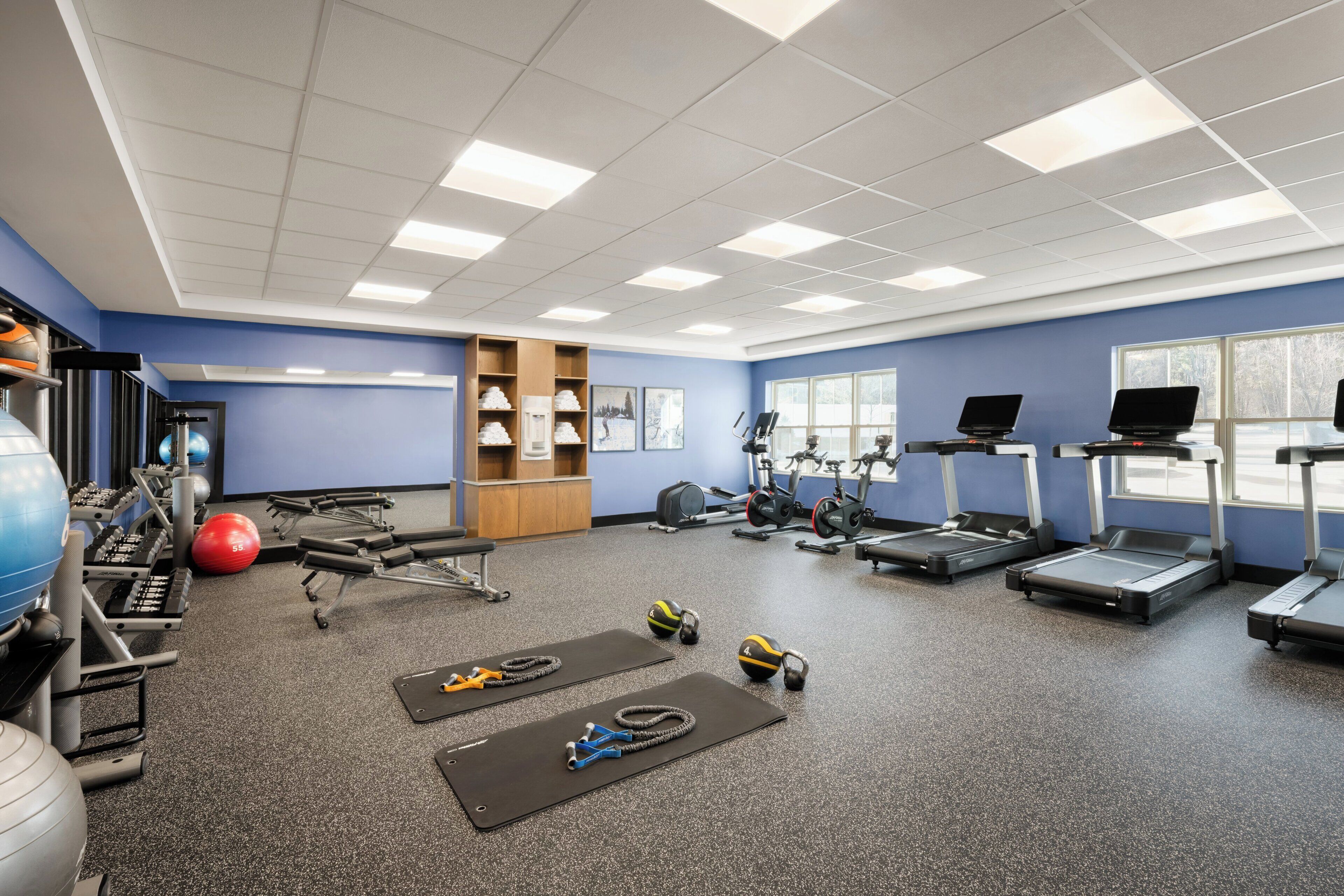 Une salle de sport équipée de matériel d’exercice, de tapis de course et dotée d’un mur bleu.