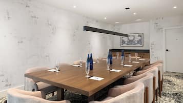 Un salón de conferencias con una larga mesa de madera, seis sillas tapizadas y una lámpara colgante moderna.