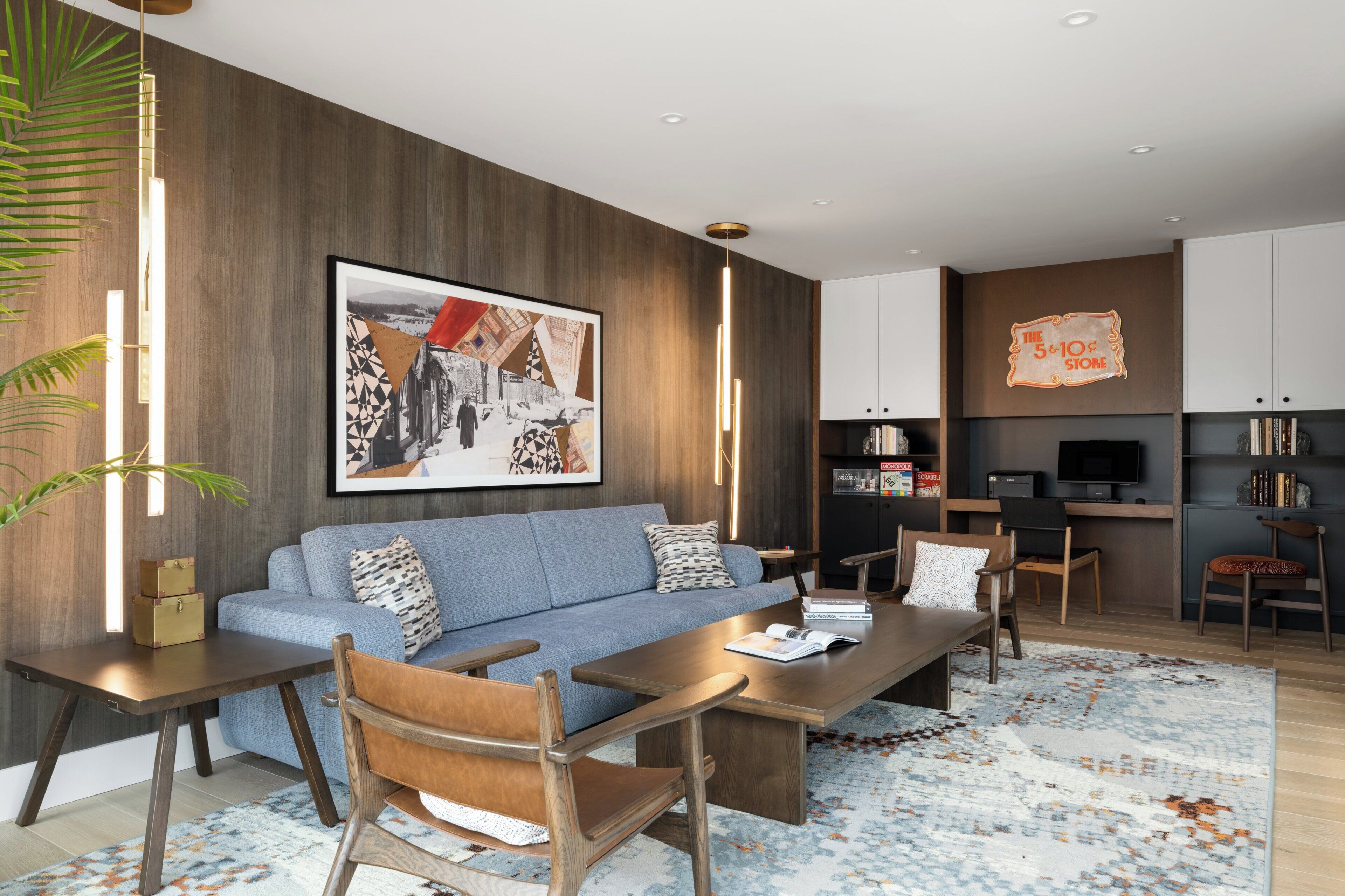 A modern living room with a sofa, coffee table, chairs, a TV, and a kitchen area.