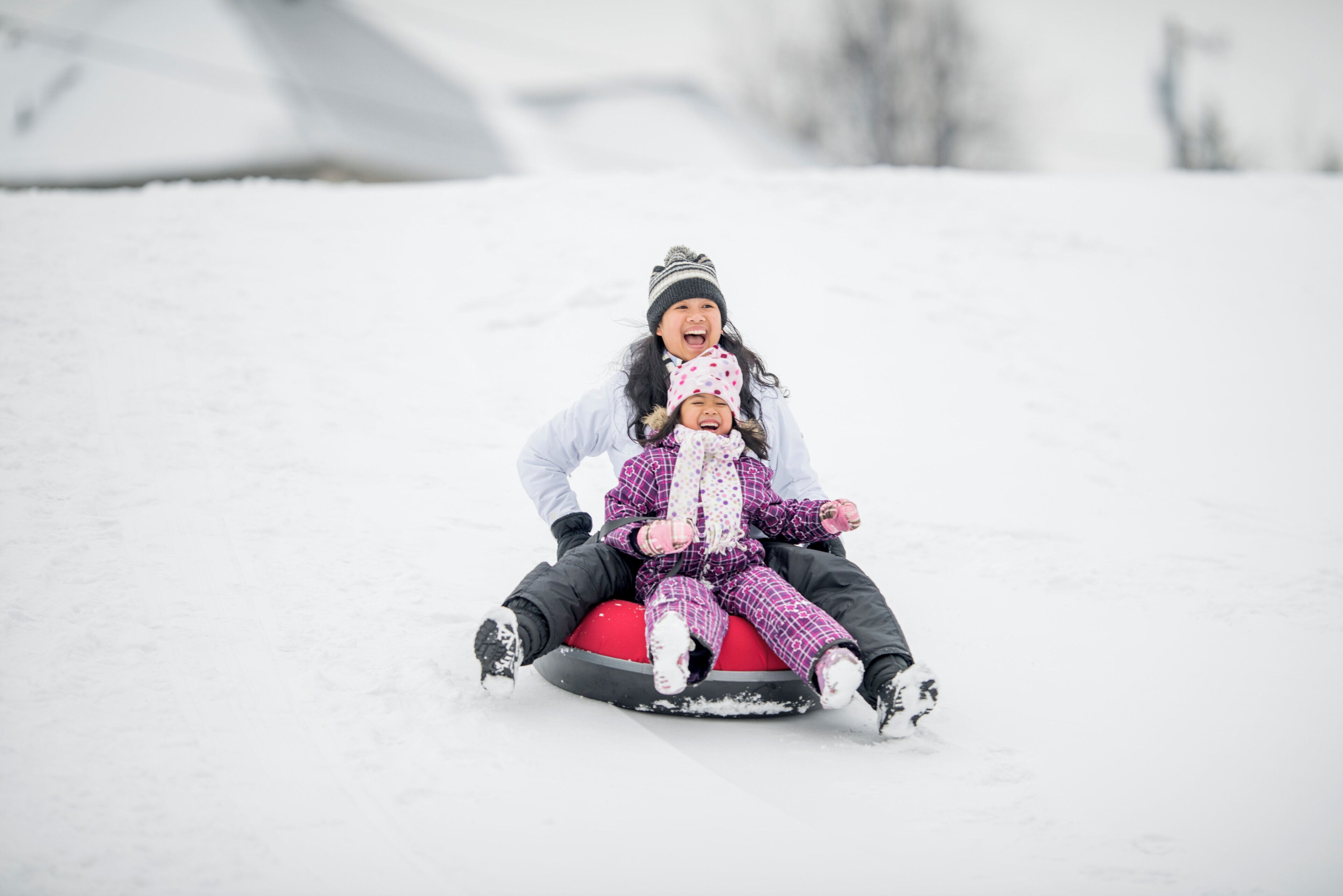 Two people sledding down a snowy slope.