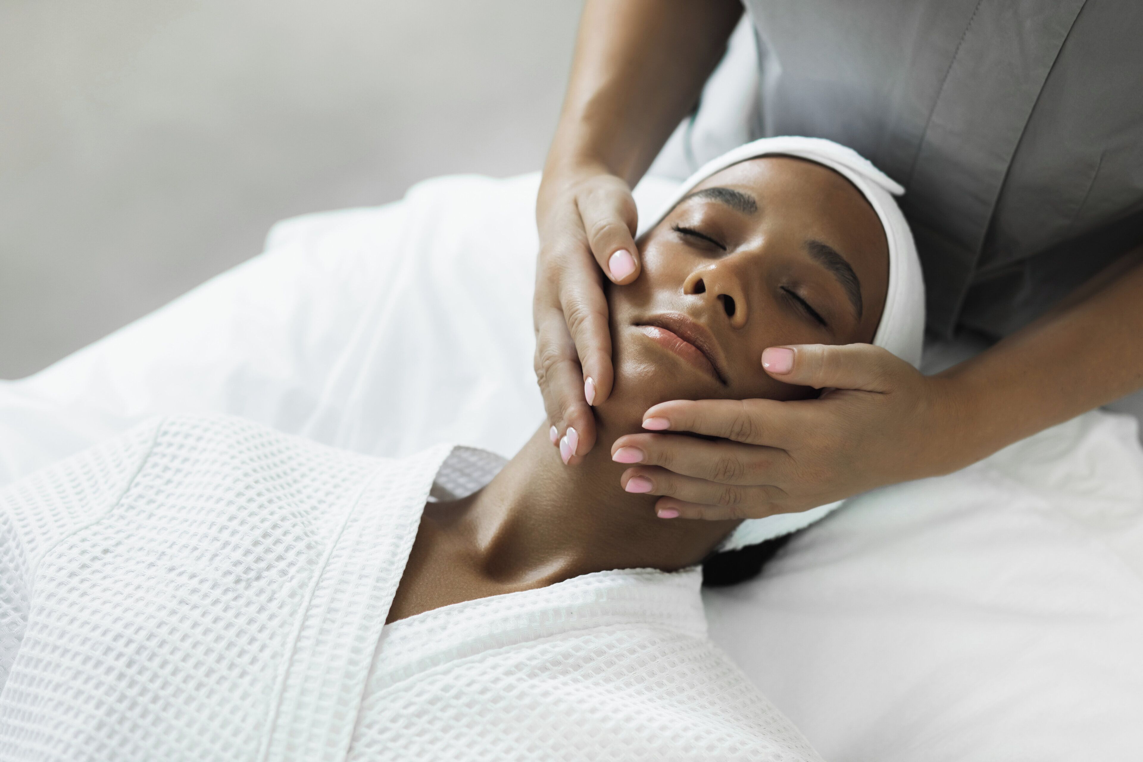 A person lying on a bed with a white textured blanket, receiving a massage.
