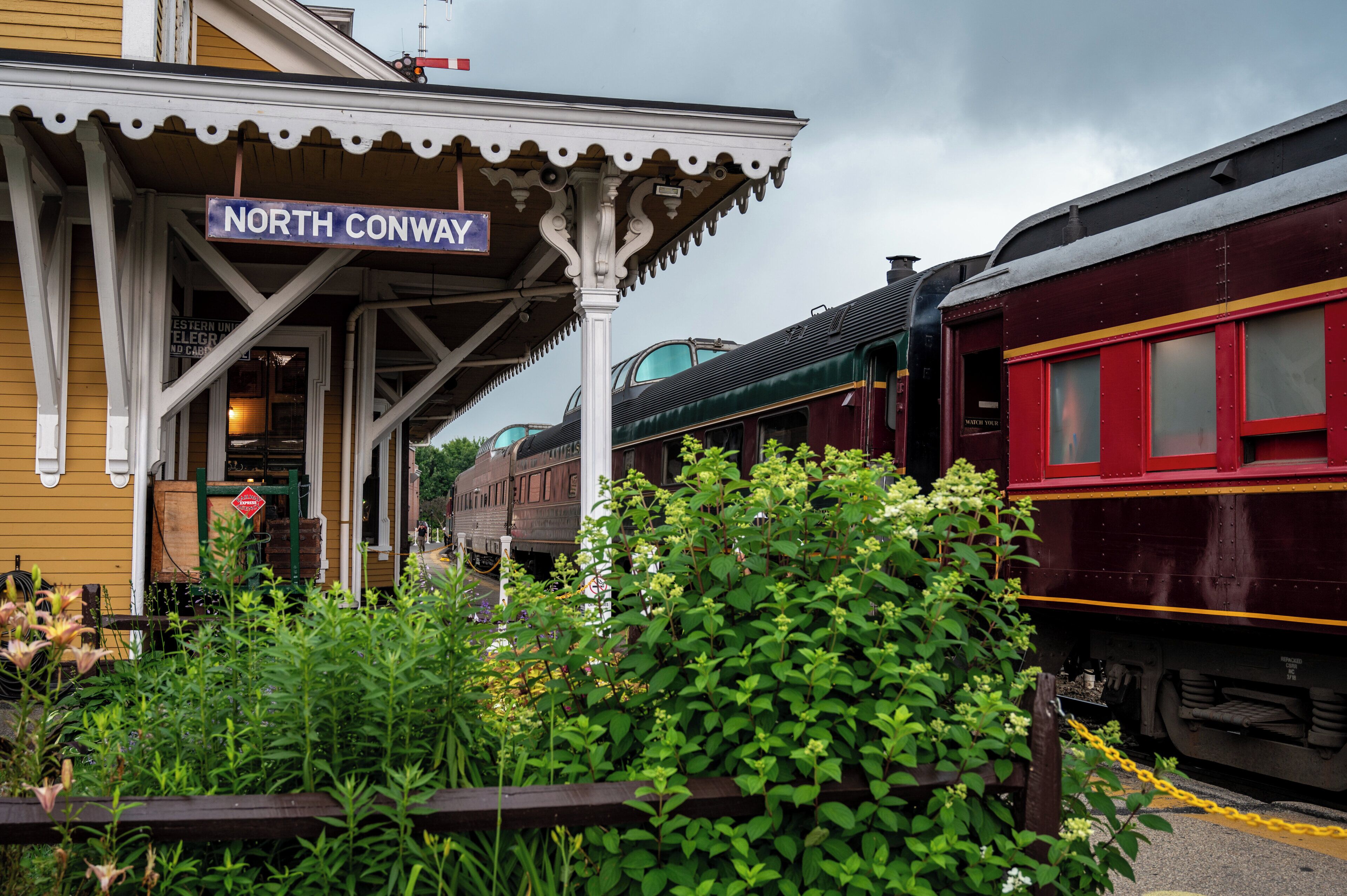 A train station platform with a sign reading "North Conway".