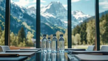 A conference table with water bottles and documents, overlooking a mountainous landscape through large windows.
