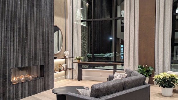 Una sala de estar moderna con un sofá grande, una chimenea y vistas a un paisaje nevado a través de amplios ventanales.