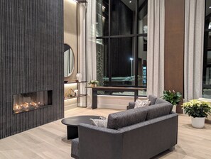 Una sala de estar moderna con un sofá grande, una chimenea y vistas a un paisaje nevado a través de amplios ventanales.