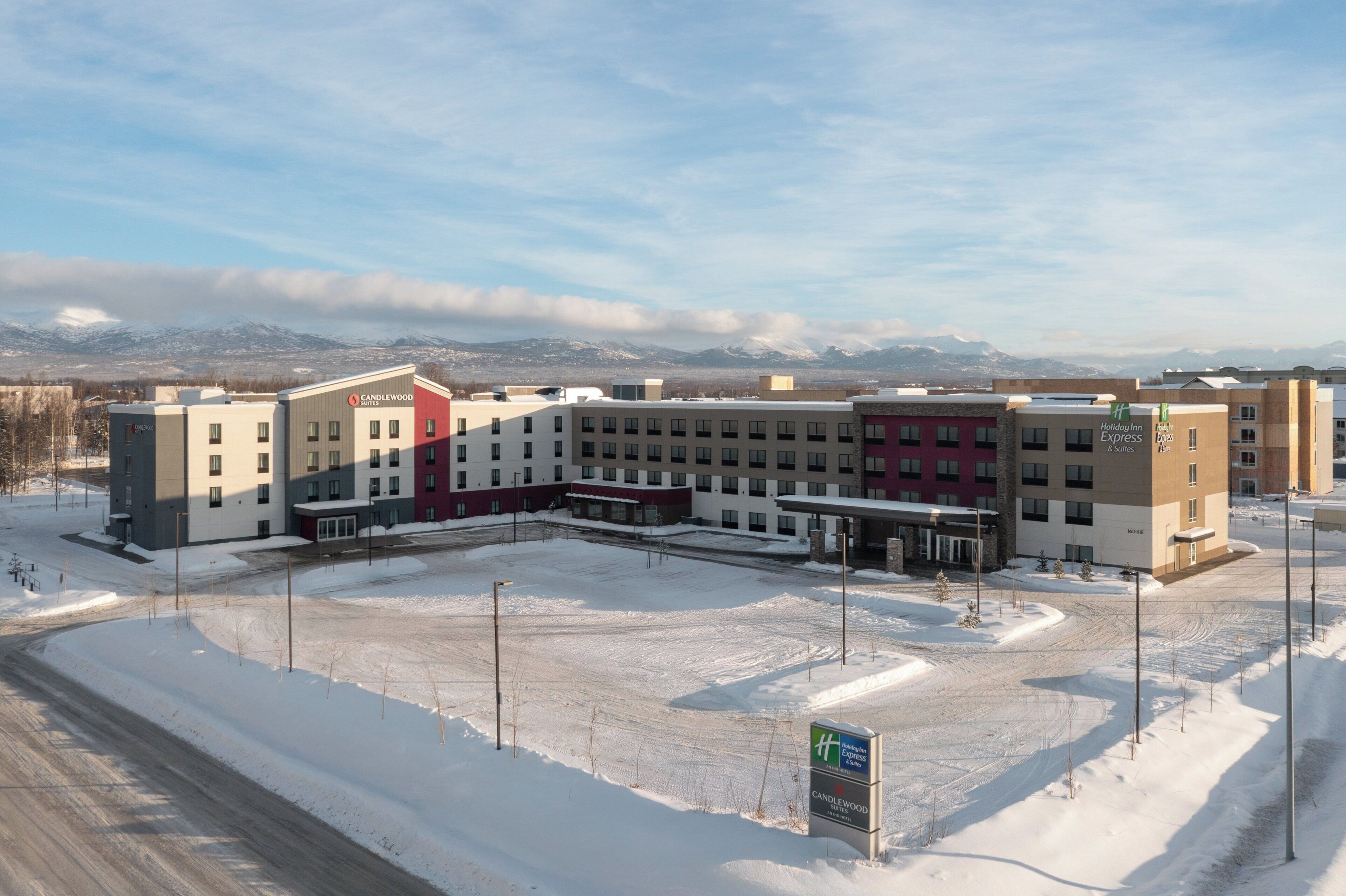 A multi-story hotel with a central courtyard, surrounded by snow-covered ground, and a mountain range in the background.