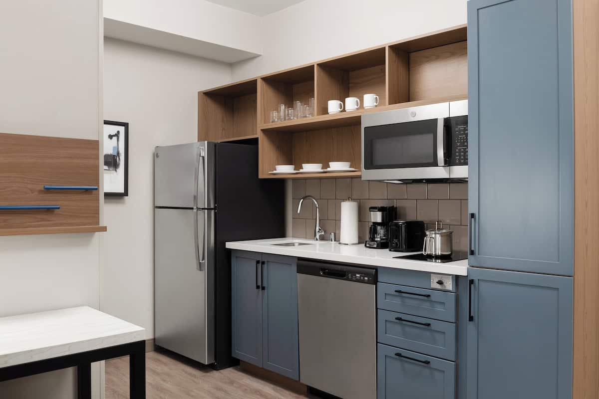 Una cocina moderna con refrigerador, microondas, cafetera y pileta.