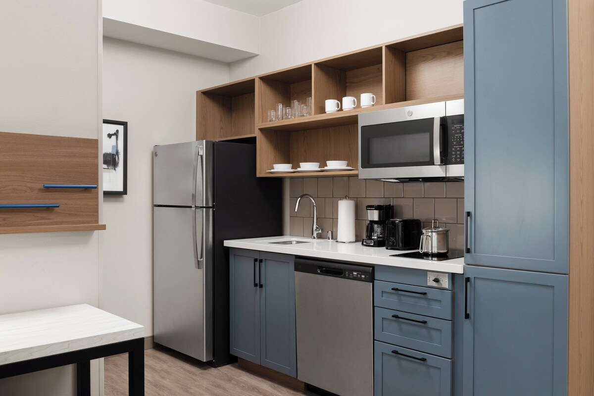 A modern kitchen with a refrigerator, microwave, coffee maker, and a sink.