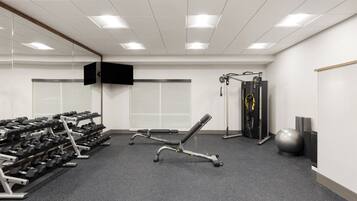 A gym with weightlifting equipment, a bench, and a cable machine.