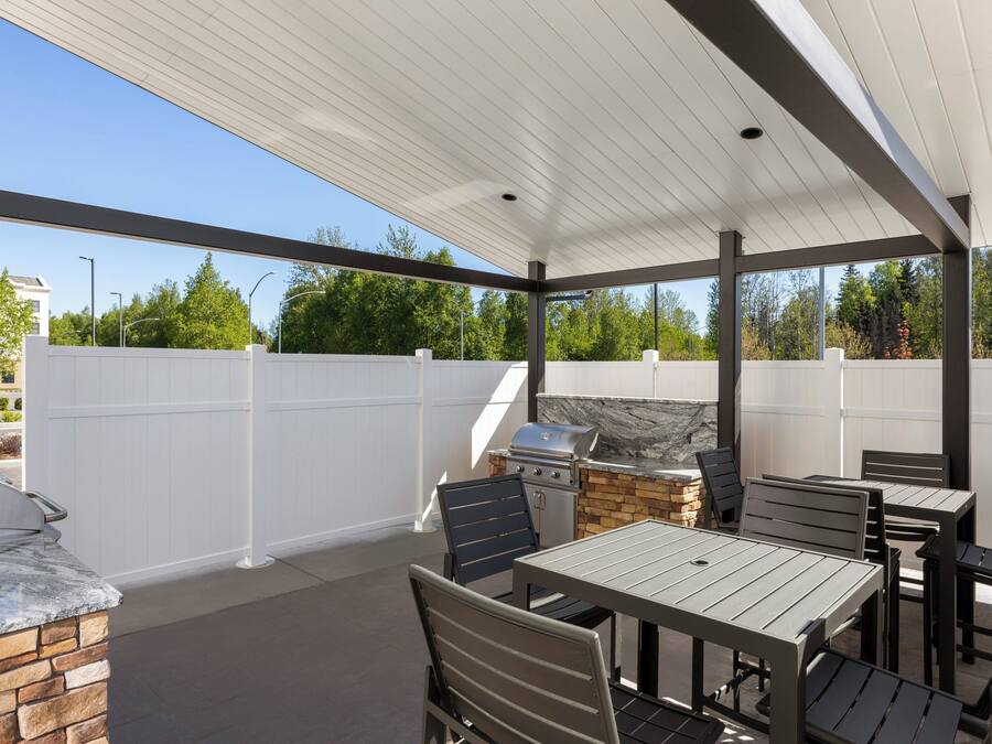 An outdoor patio with a grill, stone fireplace, and seating area.
