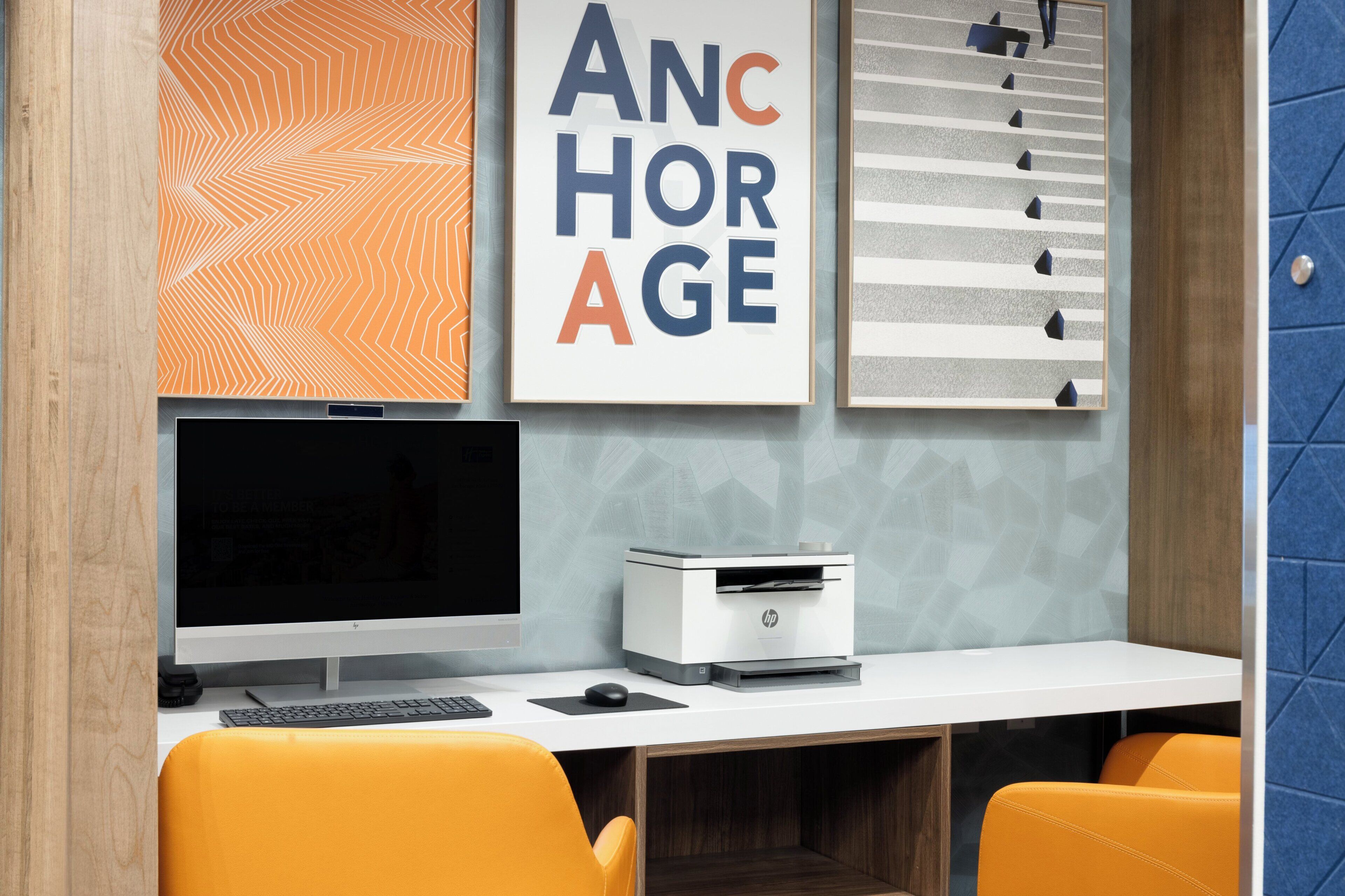 A modern office desk with a computer, printer, and two chairs.