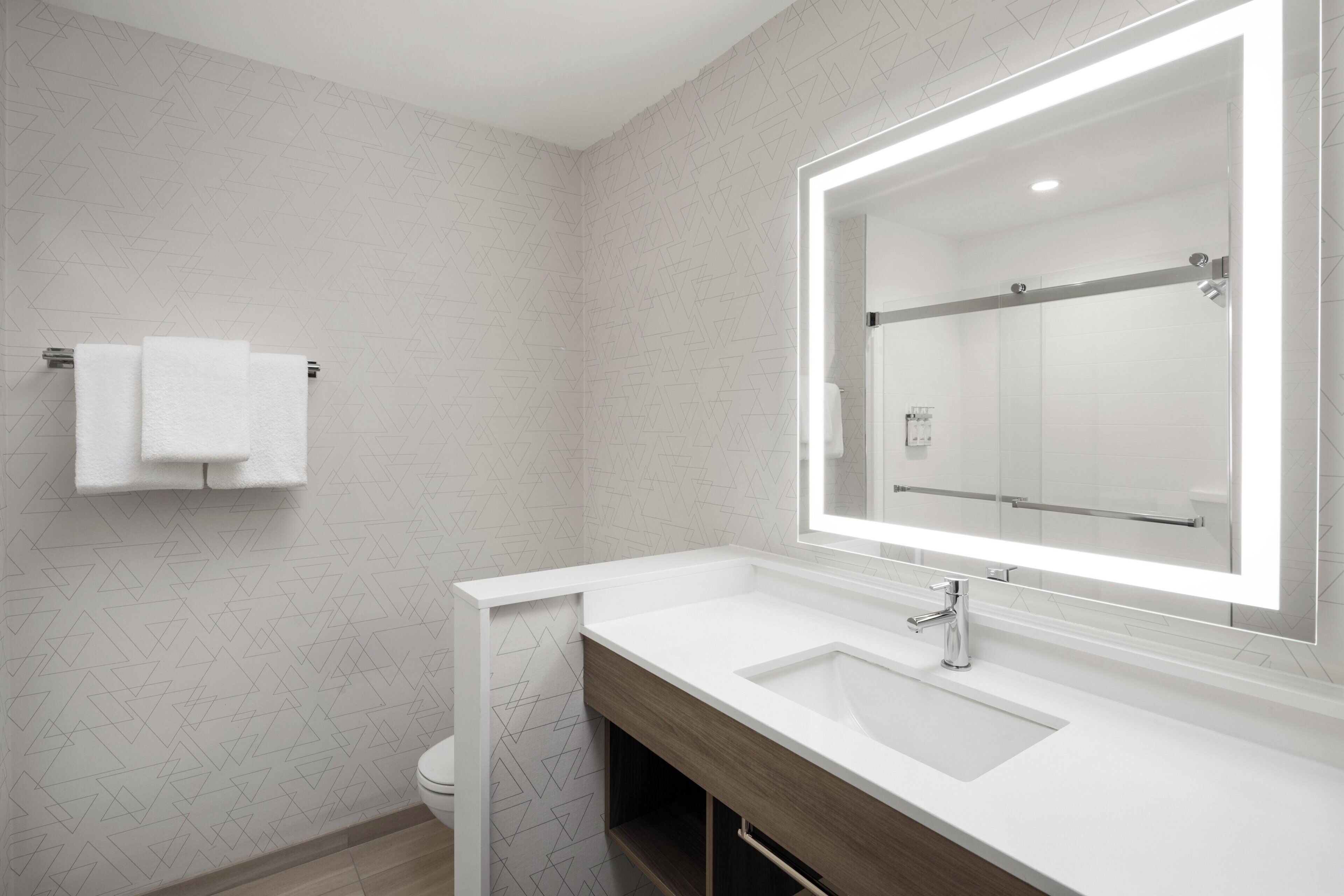 Une salle de bain moderne avec un lavabo blanc, un grand miroir et un porte-serviettes.