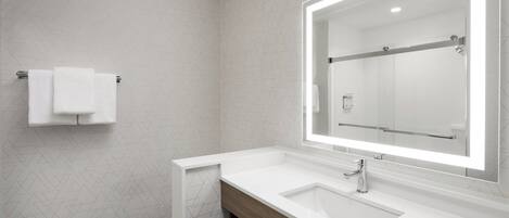 Une salle de bain moderne avec un lavabo blanc, un grand miroir et un porte-serviettes.