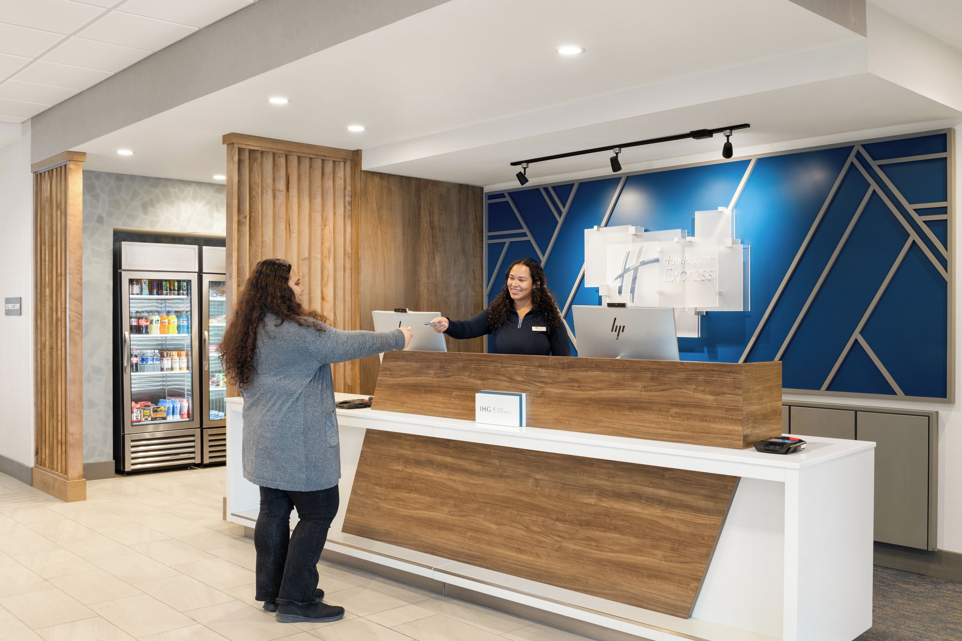 A reception desk with a wooden finish, a digital screen, and a sign indicating 'IHG Express.'