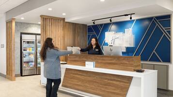 A reception desk with a wooden finish, a digital screen, and a sign indicating 'IHG Express.'
