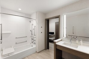 Un baño moderno con bañera, ducha, tocador y un espejo grande.