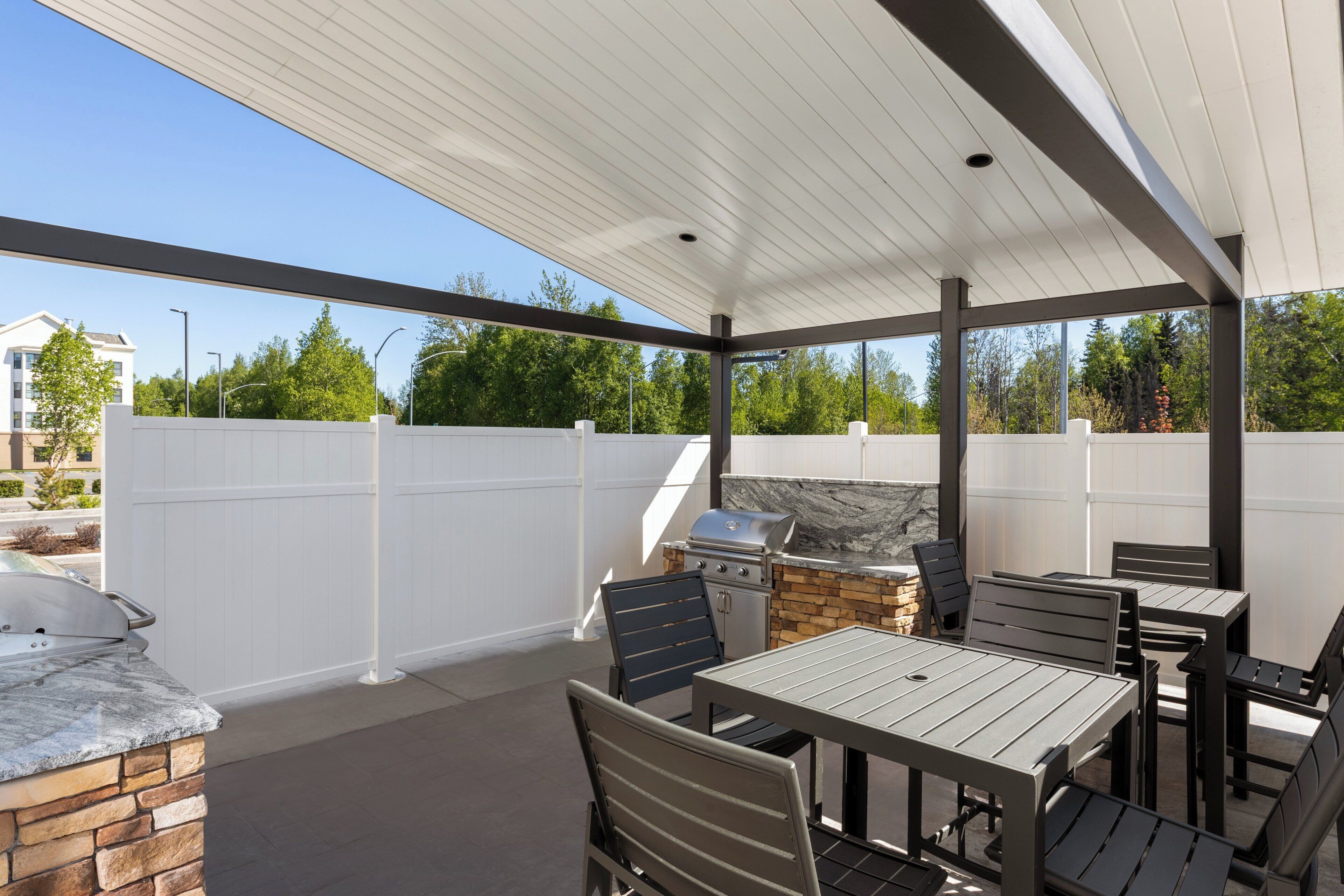 An outdoor patio area with a grill, seating, and a stone fireplace.
