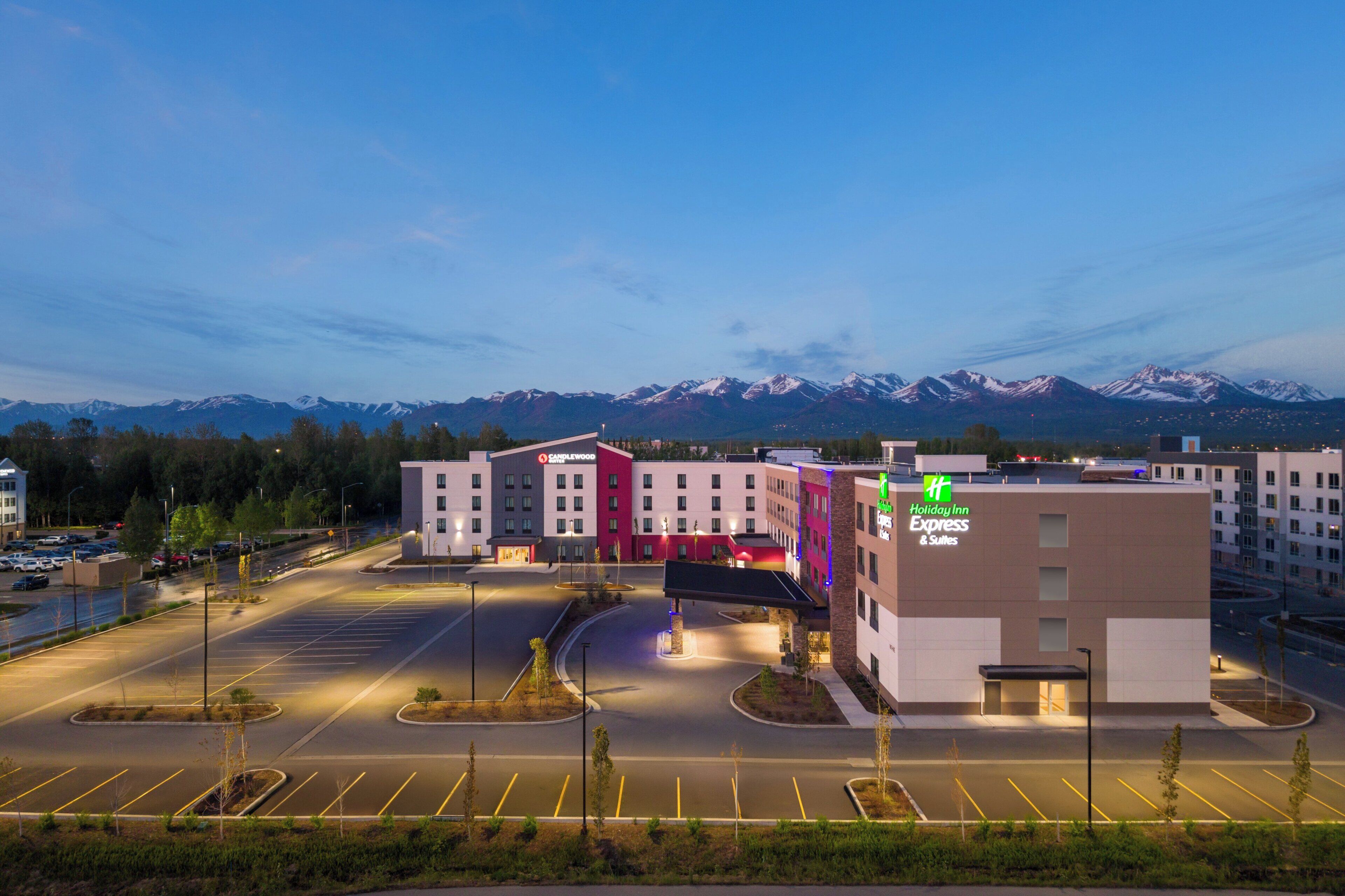 A Holiday Inn Express & Suites hotel with a parking lot and a mountainous backdrop.