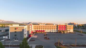 A hotel with a modern design, a parking lot, and a view of mountains in the background.